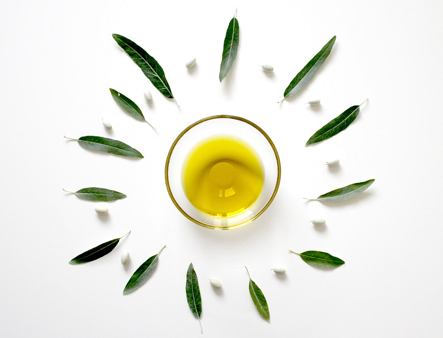 Top View of Olive Oil Bowl with Leaves and Garlic