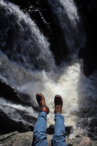 First person view of hiking boots dangling over a waterfall