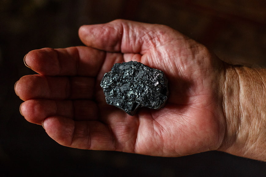 Hand holding raw black mineral stone specimen