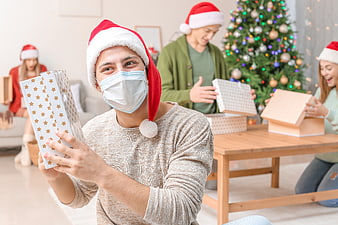 Man with Santa Hat and Face Mask Opening Christmas Gift