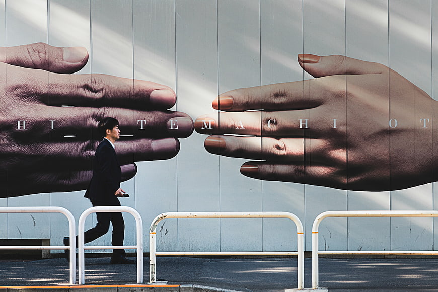 Man walking past giant hand mural on city wall
