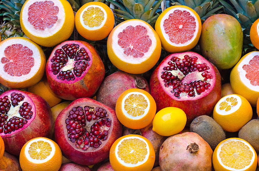 Vibrant Flat Lay of Fresh Cut Pomegranates, Oranges, and Grapefruits