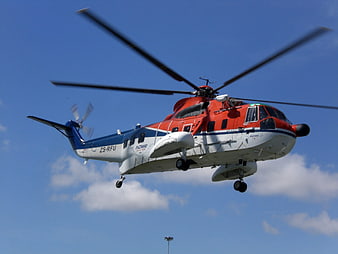 Red and white rescue helicopter flying in blue sky