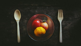 Top view of fresh fruit in a glass bowl with wooden cutlery