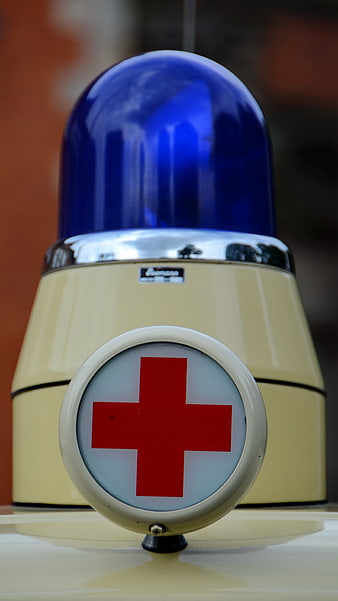 Close-up of vintage ambulance blue light and red cross symbol