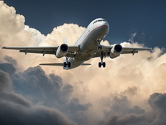 Low-angle view of white airplane landing through clouds