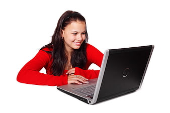 Young woman in red sweater smiling at laptop on white background
