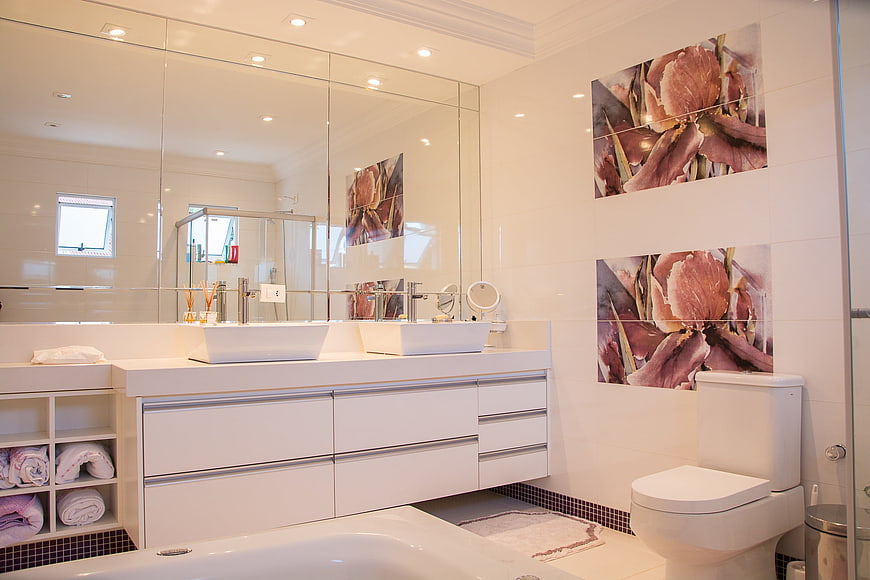 Modern white bathroom with double vanity and floral wall art
