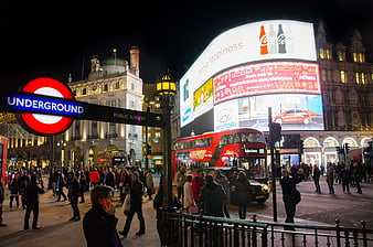 Night view of Piccadilly Circus London with red bus and underground sign
