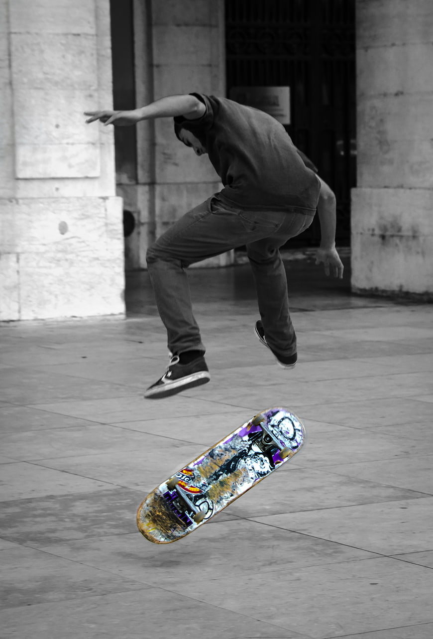 Skateboarder performing trick with selective color board