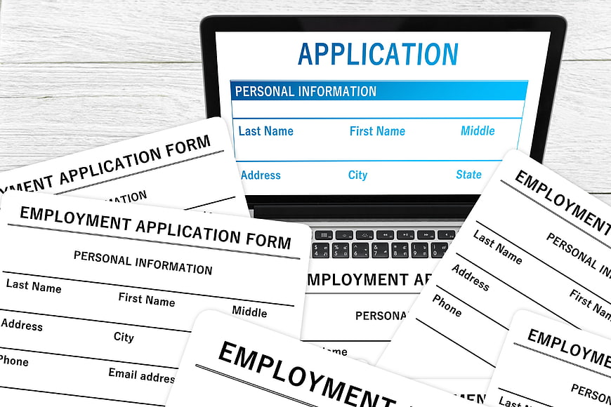 Employment Application Forms On Laptop Screen And White Wooden Desk