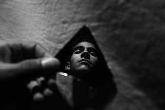 Man's reflection in a broken mirror shard in black and white