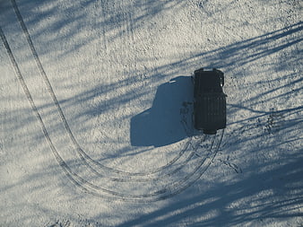 Aerial view of black SUV drifting in snow with tire tracks