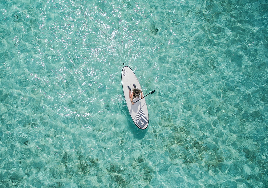 Aerial view of woman paddleboarding on turquoise ocean water