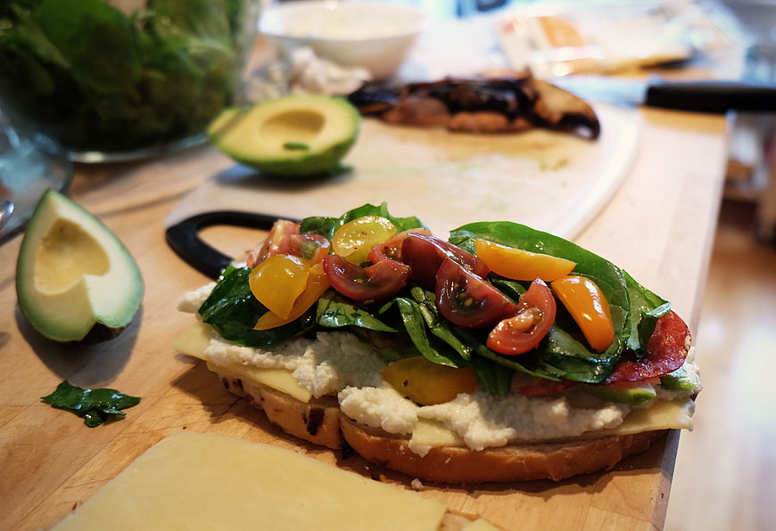 Fresh Caprese Sandwich with Avocado and Tomatoes on Wooden Board