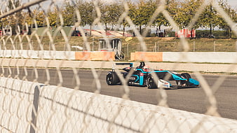 Formula E race car speeding on track through fence