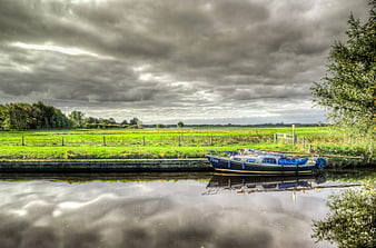 Blue Narrowboat Moored on Canal Under Dramatic Clouds