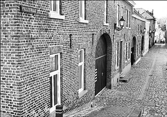 Black and white photo of historic brick buildings on a cobblestone street