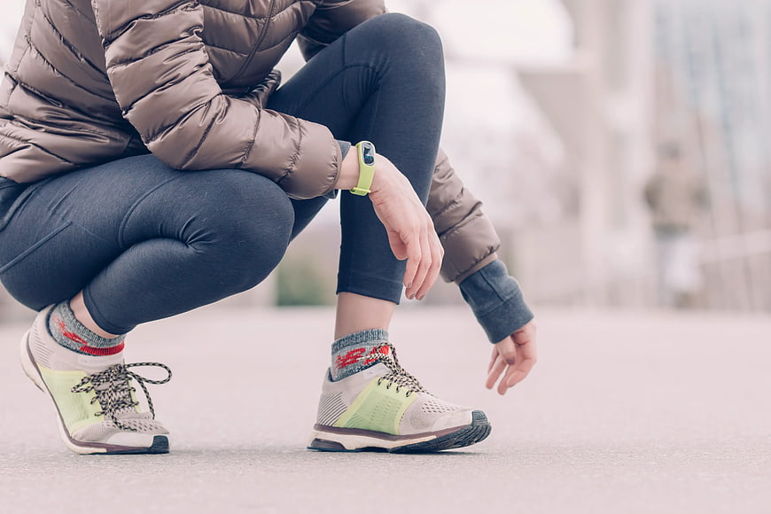 Runner Checking Smartwatch While Squatting Outdoors