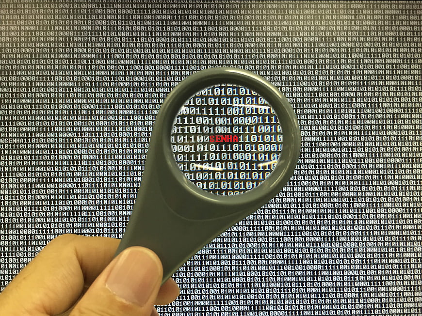 Magnifying glass inspecting binary code on computer screen
