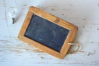 Rustic Wooden Chalkboard with Light Bulb on White Table