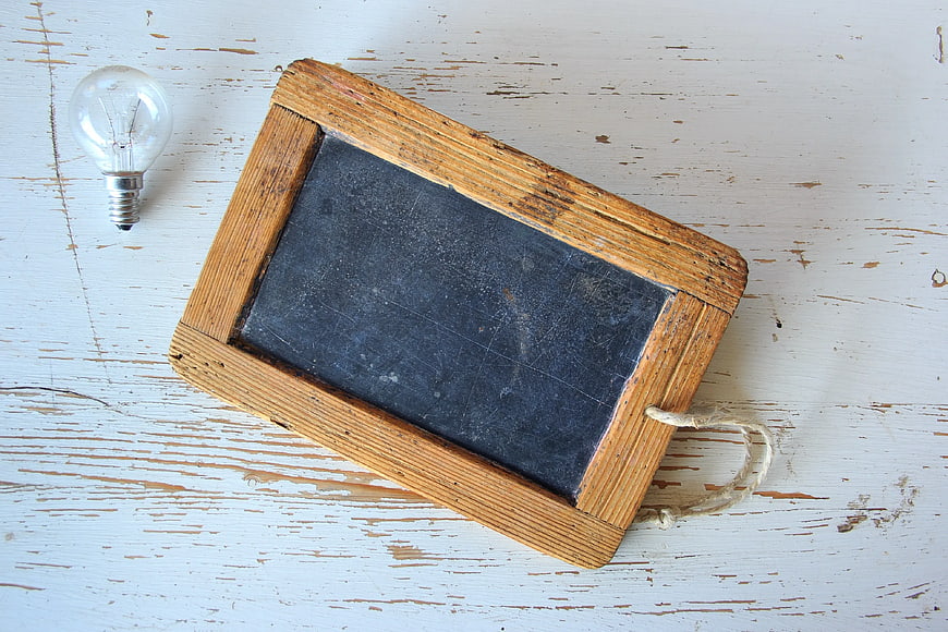 Rustic Wooden Chalkboard with Light Bulb on White Table