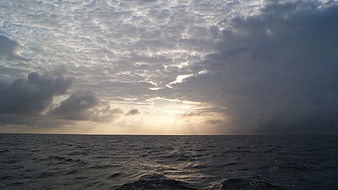 Dramatic sunset over ocean with sun rays through clouds