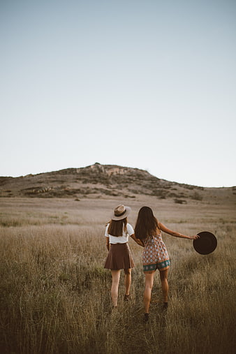 Two women walking away in a dry grassy field