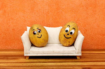 Funny potatoes with faces sitting on a miniature sofa