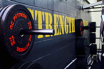 Close-up of gym barbell weights with strength text on wall