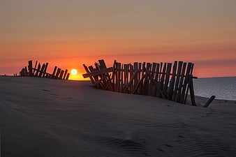 Wooden Fence Silhouette on Sand Dune at Sunset