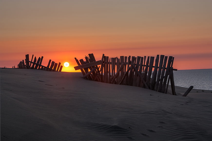 Wooden Fence Silhouette on Sand Dune at Sunset