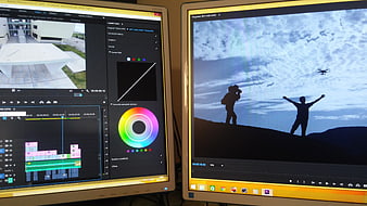 Video editing workspace with dual monitors showing Adobe Premiere Pro interface and drone footage