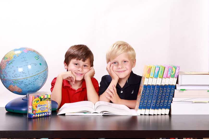 Two happy boys studying with books and globe