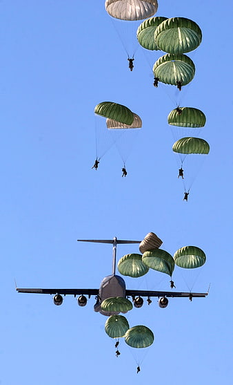 Military Paratroopers Descending From Airplane Against Blue Sky