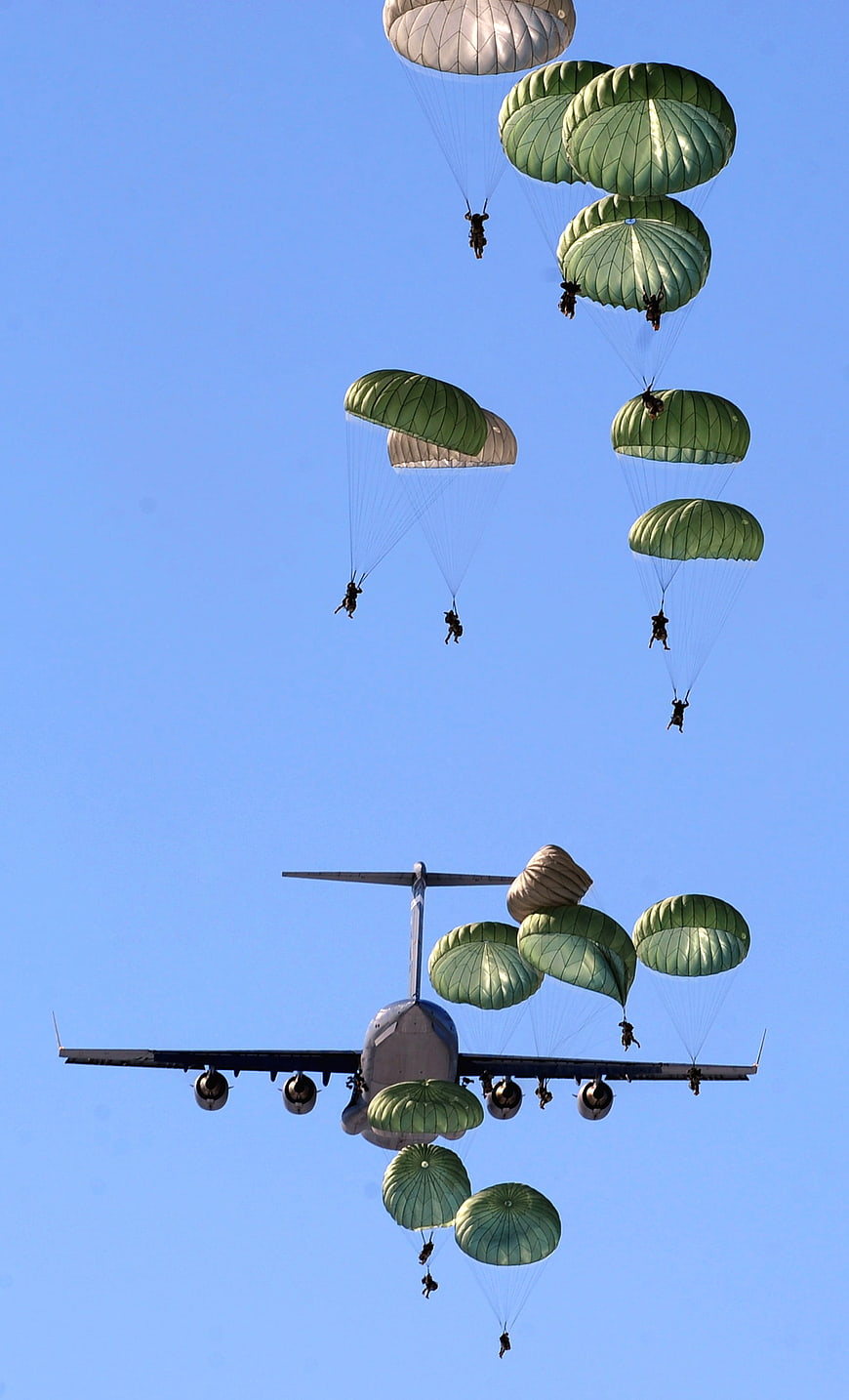 Military Paratroopers Descending From Airplane Against Blue Sky