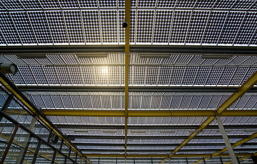 Industrial greenhouse roof with solar panels and yellow beams