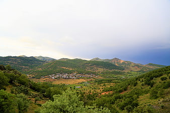 Scenic village nestled in green mountains under dramatic sky