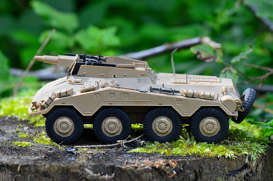 Tan Military Armored Vehicle Toy on Mossy Log