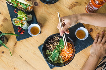 Top view of hands eating Vietnamese beef bowl with chopsticks