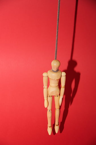 Wooden Mannequin Hanging by Rope on Red Background