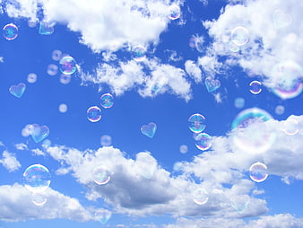 Iridescent Heart-Shaped Soap Bubbles Floating Against Blue Sky And Clouds