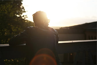 Man in Leather Jacket Looking at Sunset from Balcony