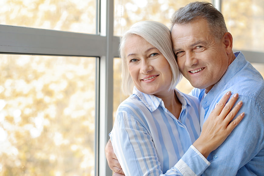 Happy Senior Couple Embracing by Window