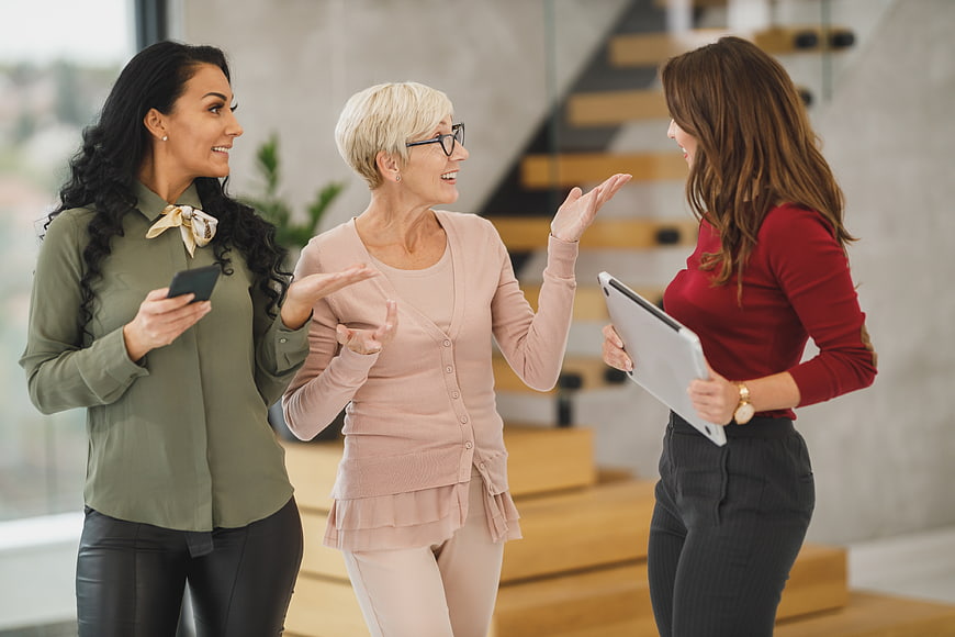 Three female colleagues discussing business in modern office
