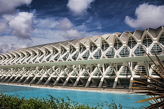 Modern white architectural structure with geometric patterns and blue water