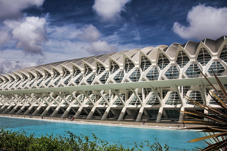 Modern white architectural structure with geometric patterns and blue water