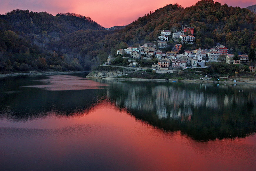 Village on Hillside Reflected in River at Sunset