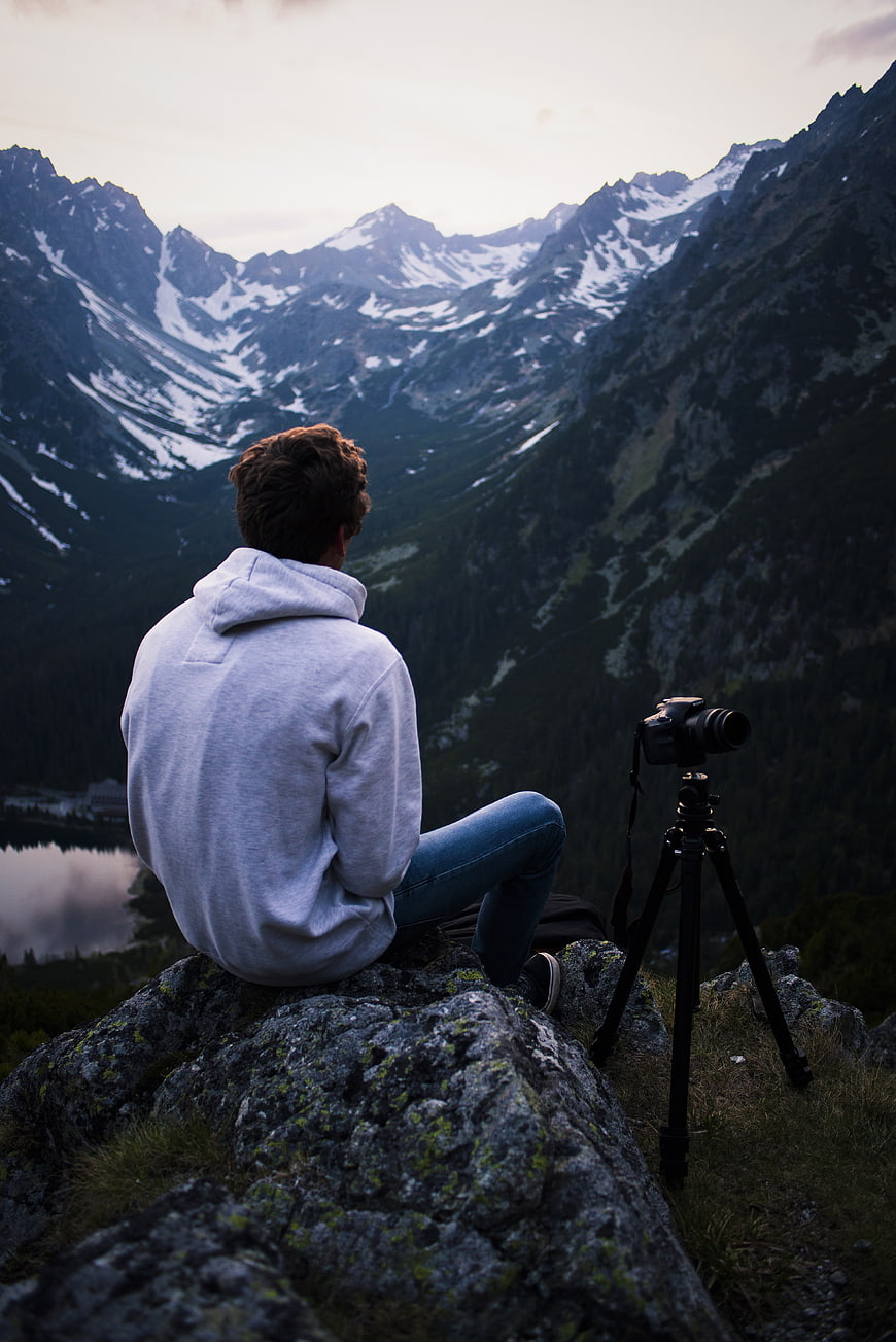 Man with Camera Tripod Overlooking Snowy Mountain Valley