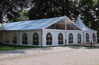 Large white event tent with arched windows on cobblestone
